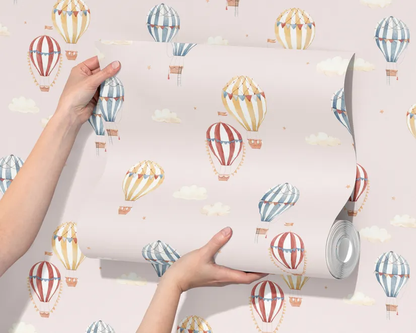 Hot air balloon nursery room wallpaper with watercolour balloons, clouds and stars on a soft blush-pink ground