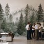 Misty mountain wallpaper mural with tall pine trees, layered green forest and pale foggy ridges