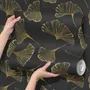 Black wallpaper with antique metallic gold ginkgo leaves on a mottled charcoal ground