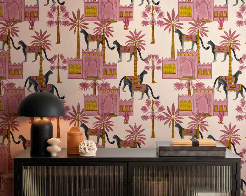 Tropical foliage wallpaper with black panthers, pink palace facades and ochre palms on pale peach