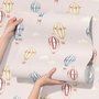Hot air balloon nursery room wallpaper with watercolour balloons, clouds and stars on a soft blush-pink ground