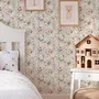 Pink wallpaper with watercolour blush, coral and yellow wildflowers, sage leaves and stems on a warm cream-white ground.