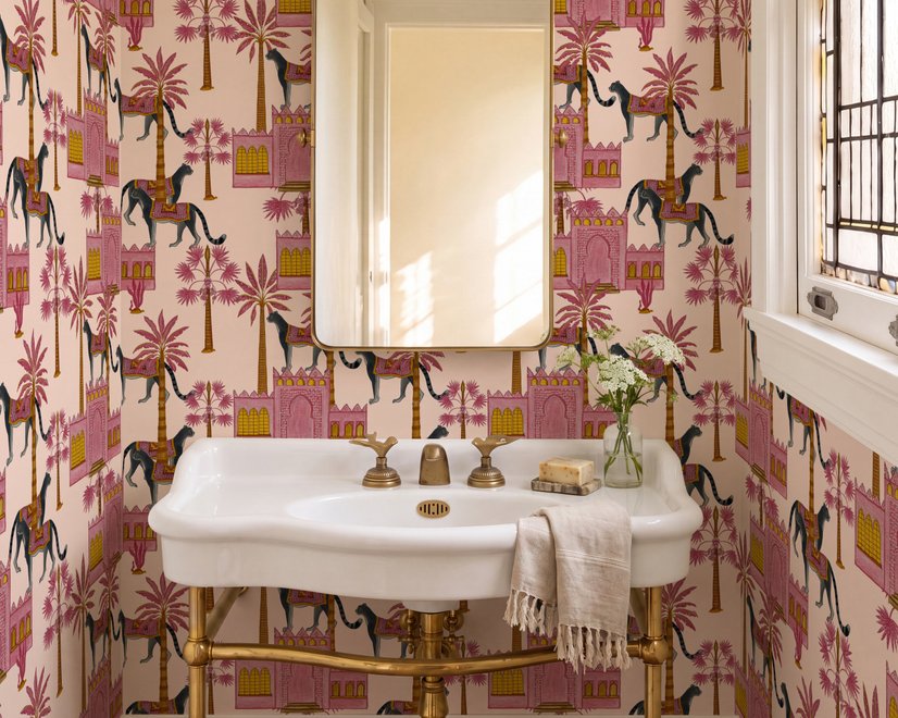 Tropical foliage wallpaper with black panthers, pink palace facades and ochre palms on pale peach