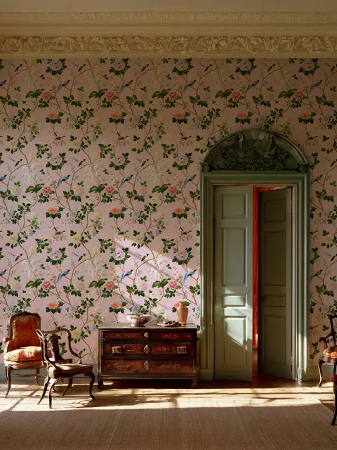Cute pink wallpaper with birds, tan branches, green leaves and ivory, coral and lilac flowers.