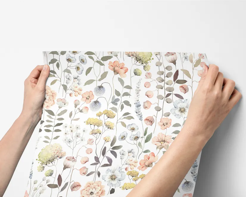 Watercolour wildflower wallpaper with pastel flowers and sage leaves on a white ground
