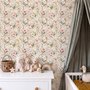 Pink wallpaper with watercolour blush, coral and yellow wildflowers, sage leaves and stems on a warm cream-white ground.