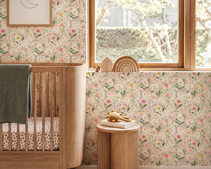 Pink wallpaper with watercolour blush, coral and yellow wildflowers, sage leaves and stems on a warm cream-white ground.
