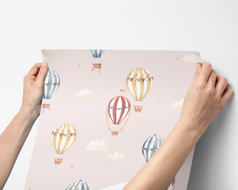 Hot air balloon nursery room wallpaper with watercolour balloons, clouds and stars on a soft blush-pink ground