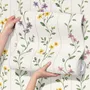 Cute floral wallpaper with green vine trails and pink, purple and yellow watercolor flowers on cream