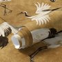 Japanese crane wallpaper with white, black and red cranes in flight on an antique-gold textured ground