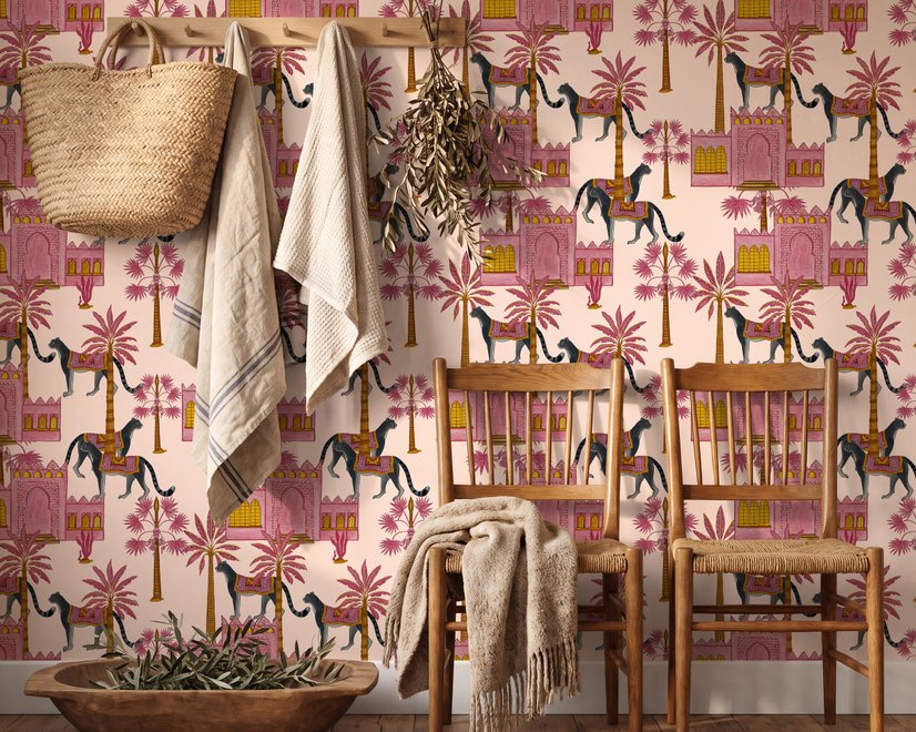 Tropical foliage wallpaper with black panthers, pink palace facades and ochre palms on pale peach