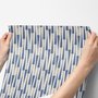Cream colored wallpaper with denim blue geometric totem stripe repeat on a linen texture ground