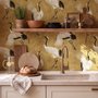 Japanese crane wallpaper with white, black and red cranes in flight on an antique-gold textured ground
