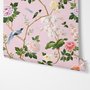 Cute pink wallpaper with birds, tan branches, green leaves and ivory, coral and lilac flowers.