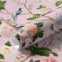 Cute pink wallpaper with birds, tan branches, green leaves and ivory, coral and lilac flowers.