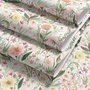 Pink wallpaper with watercolour blush, coral and yellow wildflowers, sage leaves and stems on a warm cream-white ground.