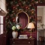 Dark moody floral wallpaper with cream peonies, coral lilies, berries and green foliage on chocolate brown