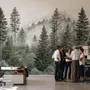 Misty mountain wallpaper mural with tall pine trees, layered green forest and pale foggy ridges