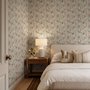 Pink wallpaper with watercolour blush, coral and yellow wildflowers, sage leaves and stems on a warm cream-white ground.