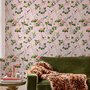 Cute pink wallpaper with birds, tan branches, green leaves and ivory, coral and lilac flowers.