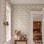 Pink wallpaper with watercolour blush, coral and yellow wildflowers, sage leaves and stems on a warm cream-white ground.