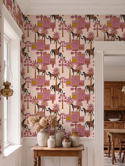 Tropical foliage wallpaper with black panthers, pink palace facades and ochre palms on pale peach