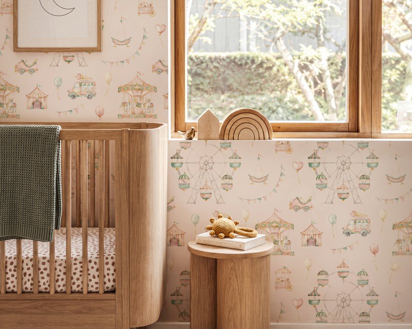 Children's playroom wallpaper with pastel Ferris wheel, carousel horses, tents and balloons on blush pink
