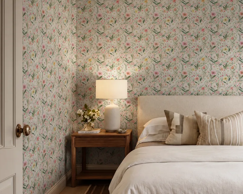 Pink wallpaper with watercolour blush, coral and yellow wildflowers, sage leaves and stems on a warm cream-white ground.