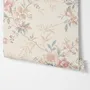 Pink chinoiserie wallpaper with watercolor flowers, blue-grey leaves and red berries on a cream linen-texture ground