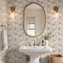 Pink wallpaper with watercolour blush, coral and yellow wildflowers, sage leaves and stems on a warm cream-white ground.